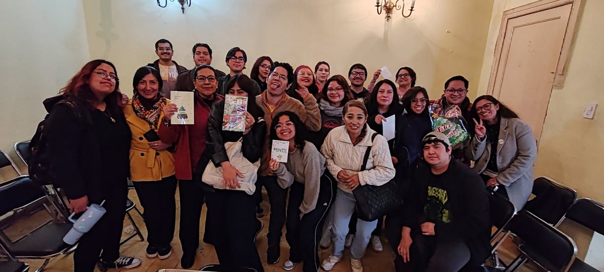Grupo grande y diverso de personas sonriendo y sosteniendo libros en un evento de lectura