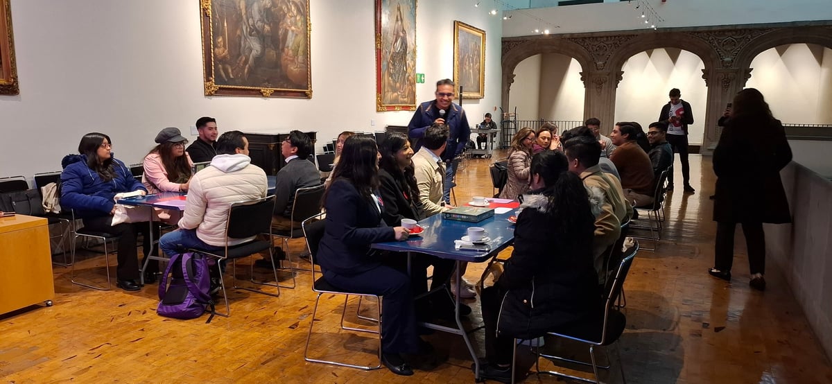 Personas reunidas en mesas redondas en una sala de museo durante una actividad de mediación